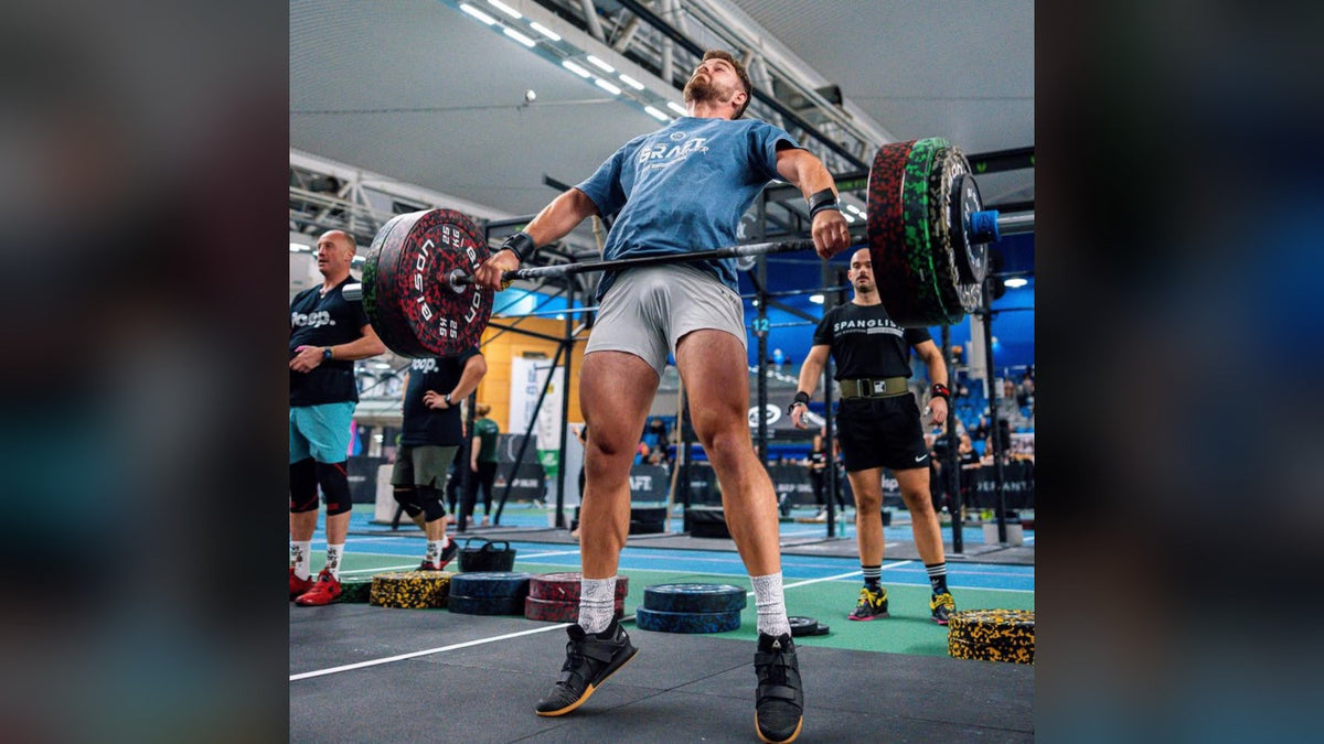Athlète CrossFit en chaussettes HEXXEE blanches soulevant une barre chargée en compétition