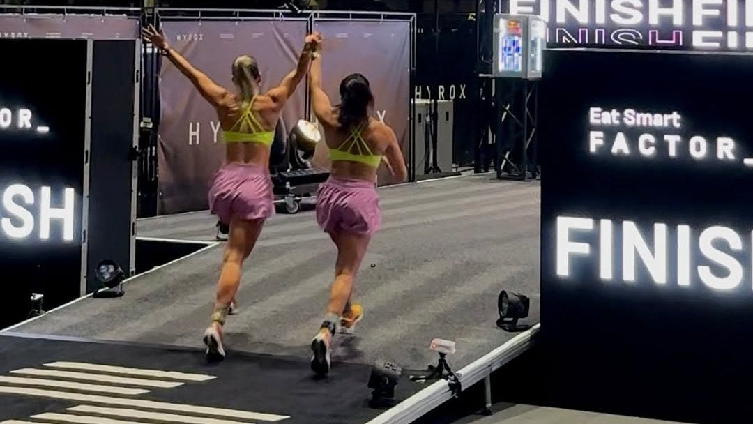 Deux athlètes HYROX en chaussettes HEXXEE franchissent la ligne d'arrivée main dans la main